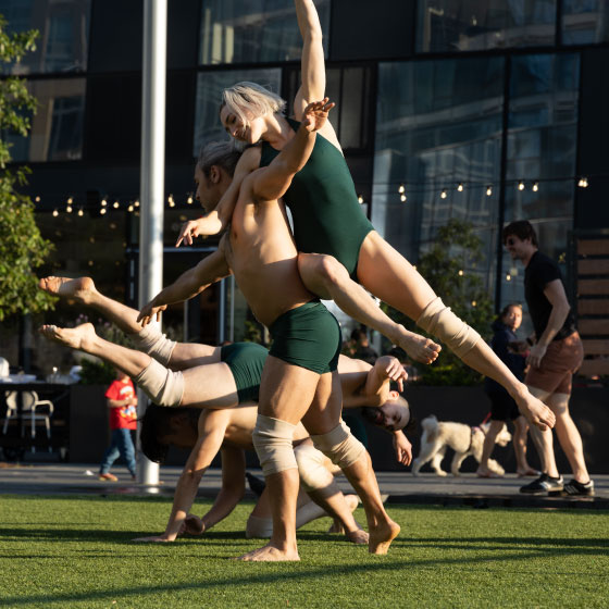 A duo of modern dancers perform an expressive outdoor routine, showcasing athleticism and grace amidst an urban backdrop.