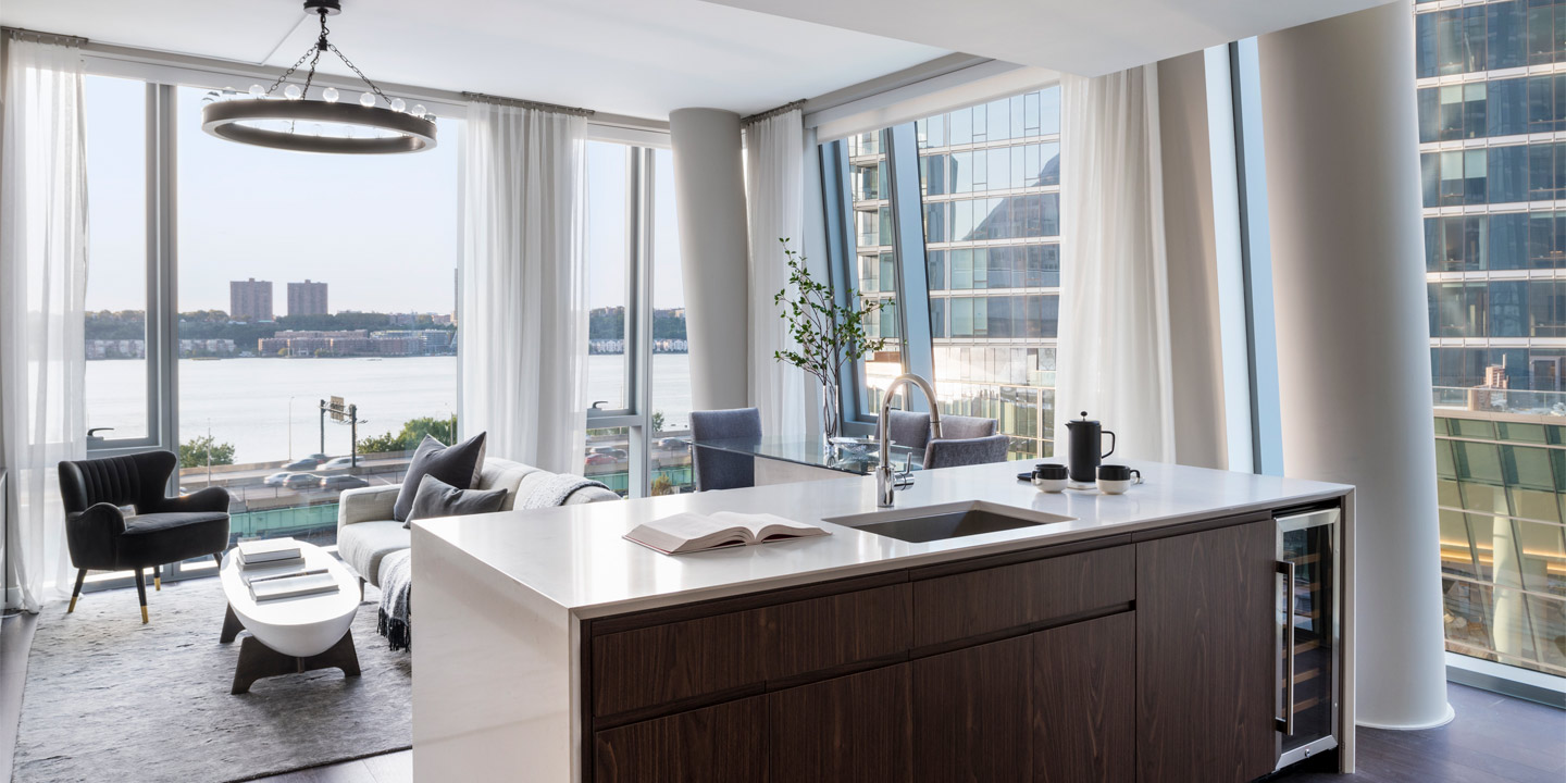 Modern apartment interior with floor-to-ceiling windows offering a stunning river view, featuring a sleek kitchen island, a cozy dining area, and an inviting living space bathed in natural light.