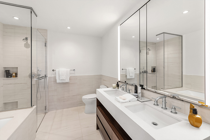 Modern bathroom with a double vanity, frameless glass shower, and clean, white tile design.