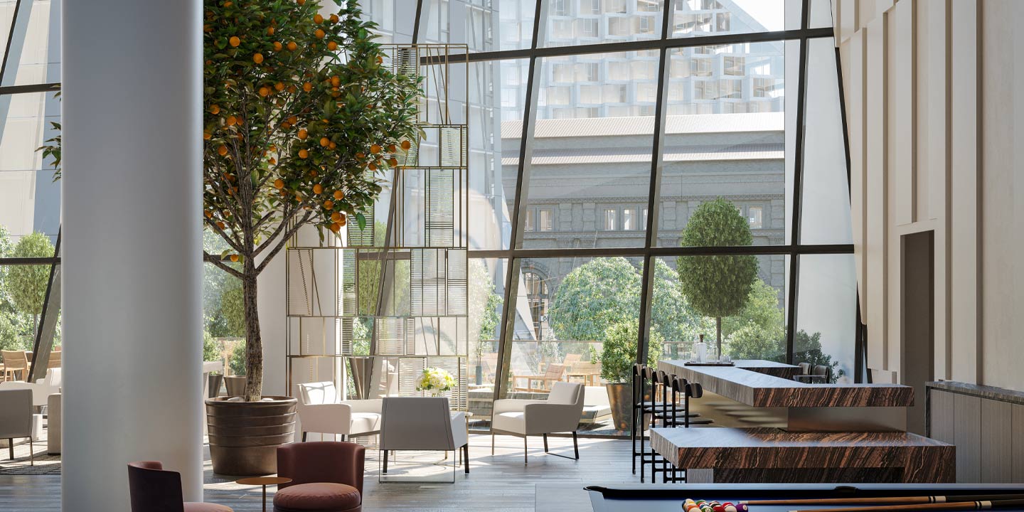 A modern and airy indoor lounge space with large windows, offering a view of urban architecture and incorporating a touch of nature with a thriving indoor orange tree.