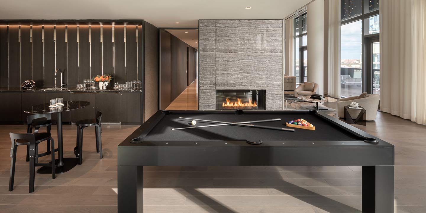 Elegant modern game room featuring a sleek black pool table with cues, elegant fireplace backdrop, and chic interior design.