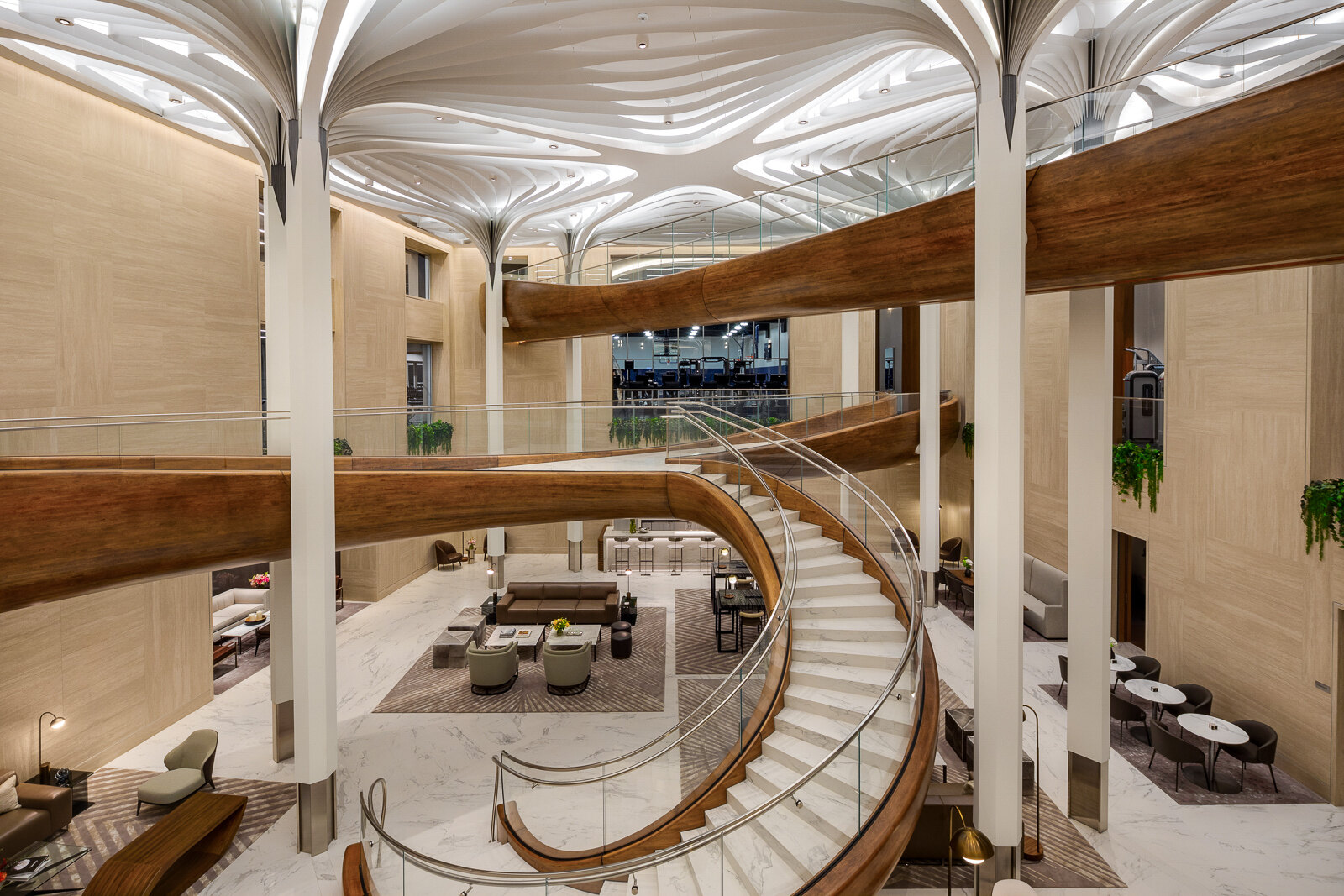 Modern hotel lobby with elegant curved staircase and striking organic design elements, showcasing a blend of natural wood accents and sleek white contours.