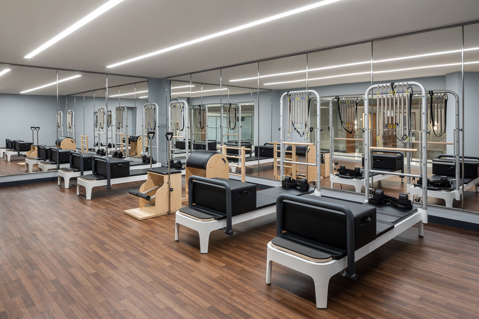 A pristine and modern pilates studio equipped with reformer machines, ready for a full-body workout session.