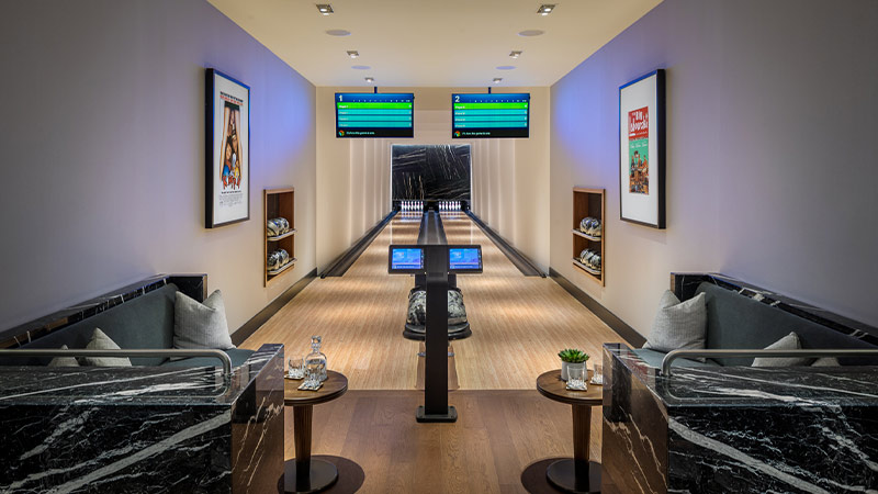A sleek and modern private bowling alley with two lanes, comfortable seating areas, and large screens displaying the scores.