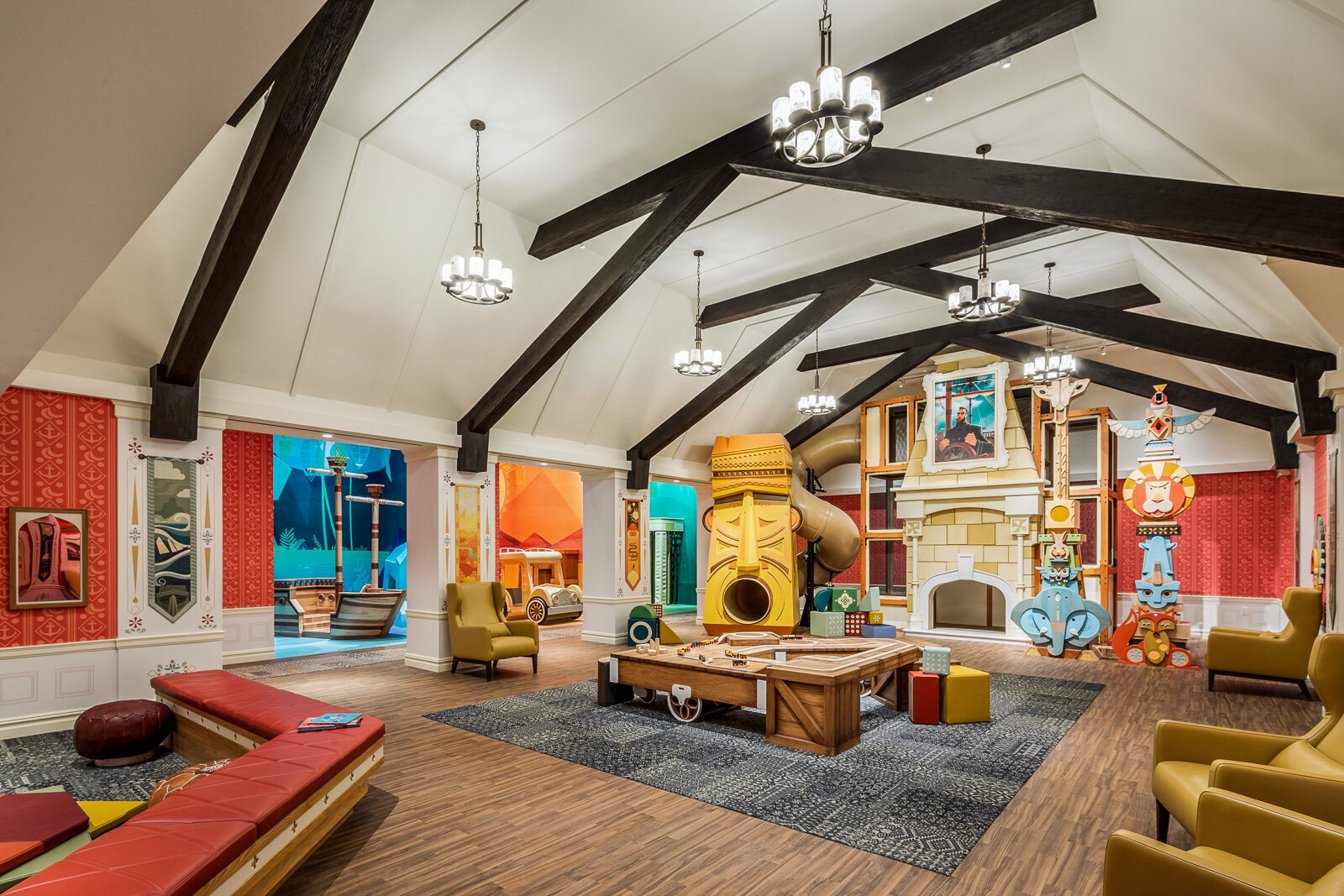 A vibrant and whimsically designed playroom with playful architecture, colorful walls, an assortment of cozy seating arrangements, and an oversized, novelty light fixture, exuding a fun and imaginative environment for children.