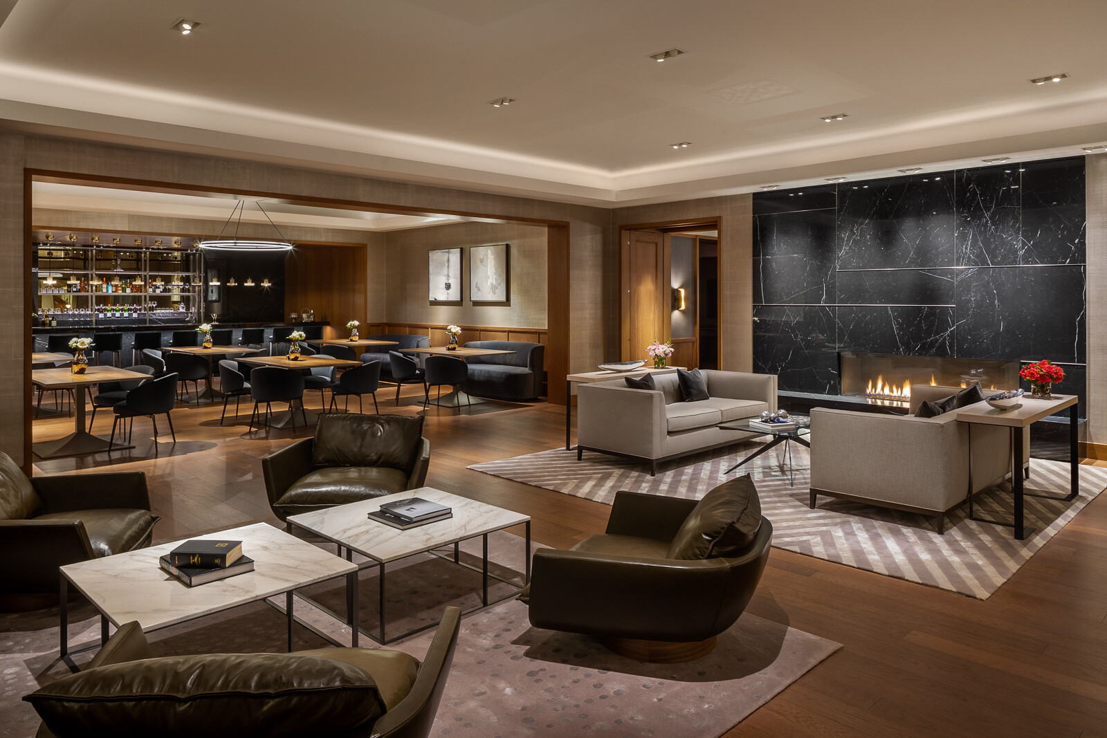 A luxurious, modern hotel lounge with stylish seating areas, a cozy fireplace, and an elegant bar in the background.