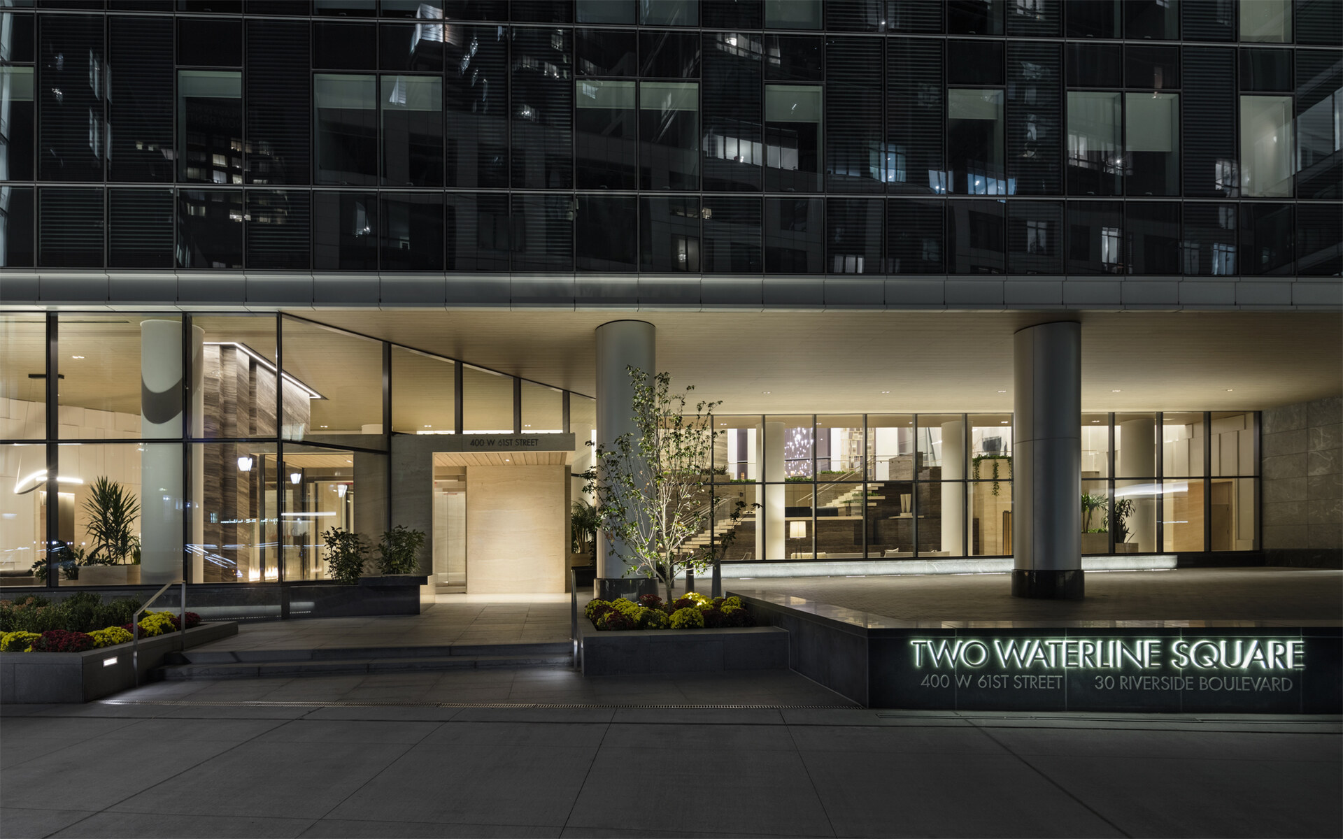 Modern urban elegance: the sleek exterior of two waterline square at night, showcasing its sophisticated lighting, well-manicured landscaping, and inviting entrance.