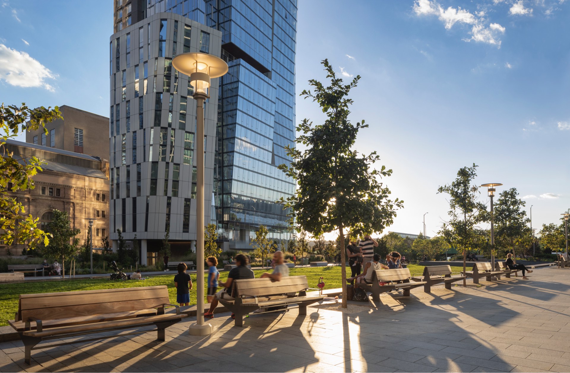 Urban oasis: residents enjoying a serene afternoon in a modern city park, surrounded by towering skyscrapers and lush greenery.