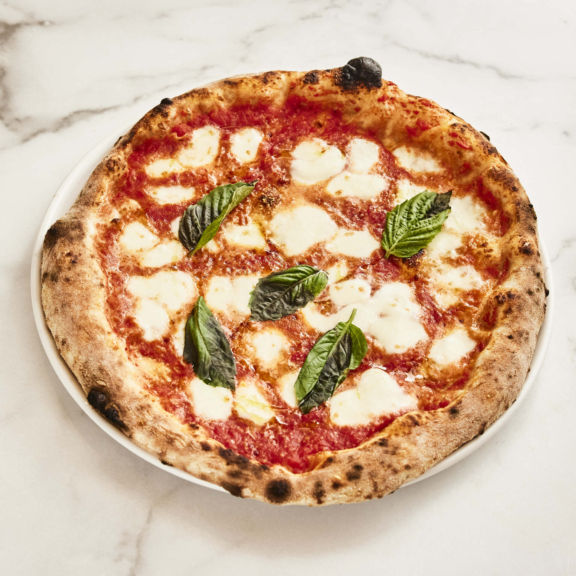 Freshly baked margherita pizza with golden crust, bright tomato sauce, melted mozzarella cheese, and vibrant basil leaves.