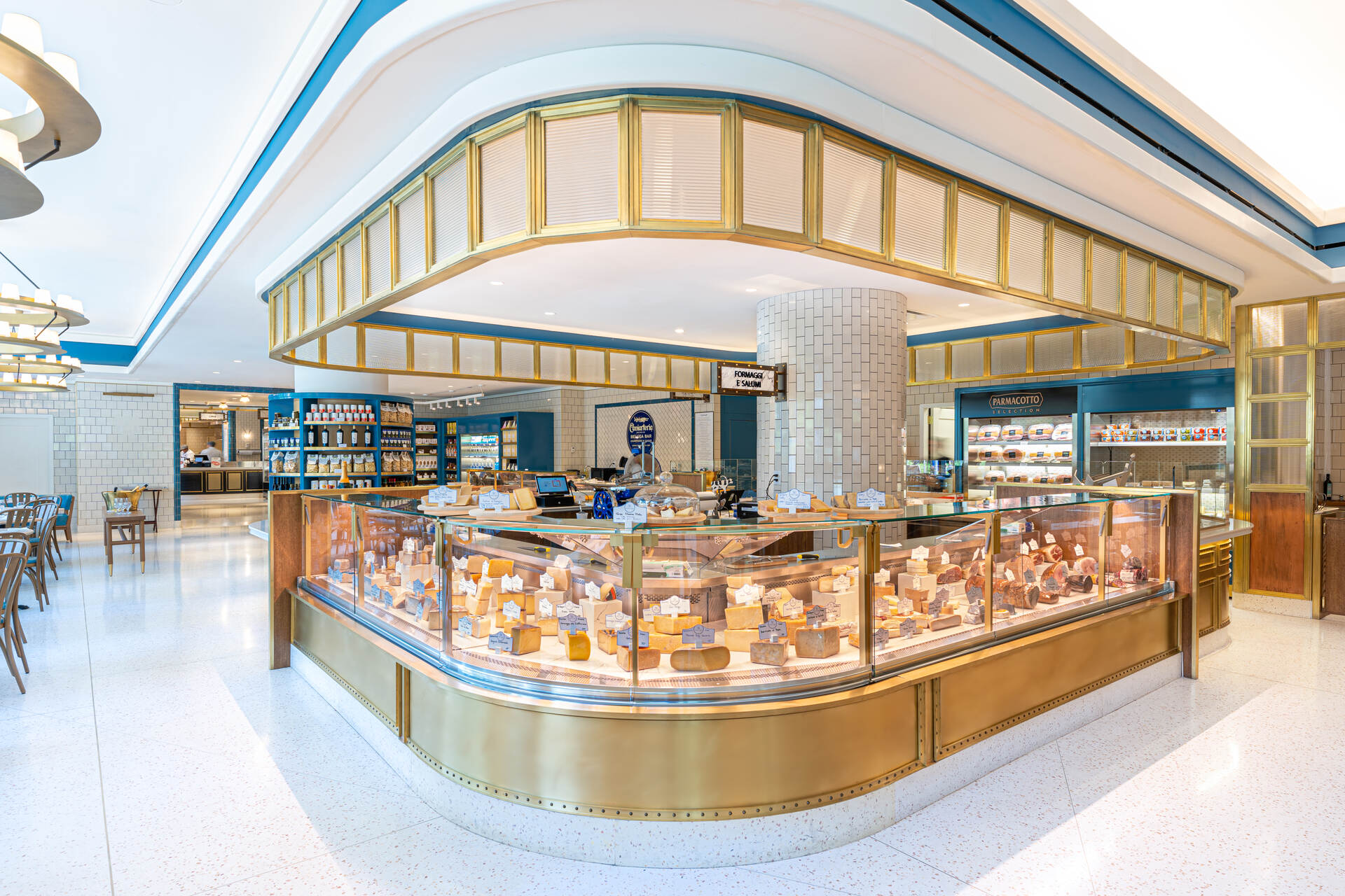 A spacious and brightly lit bakery with a modern and sleek design, featuring a large glass display case filled with an array of freshly baked goods and a cozy seating area in the background.