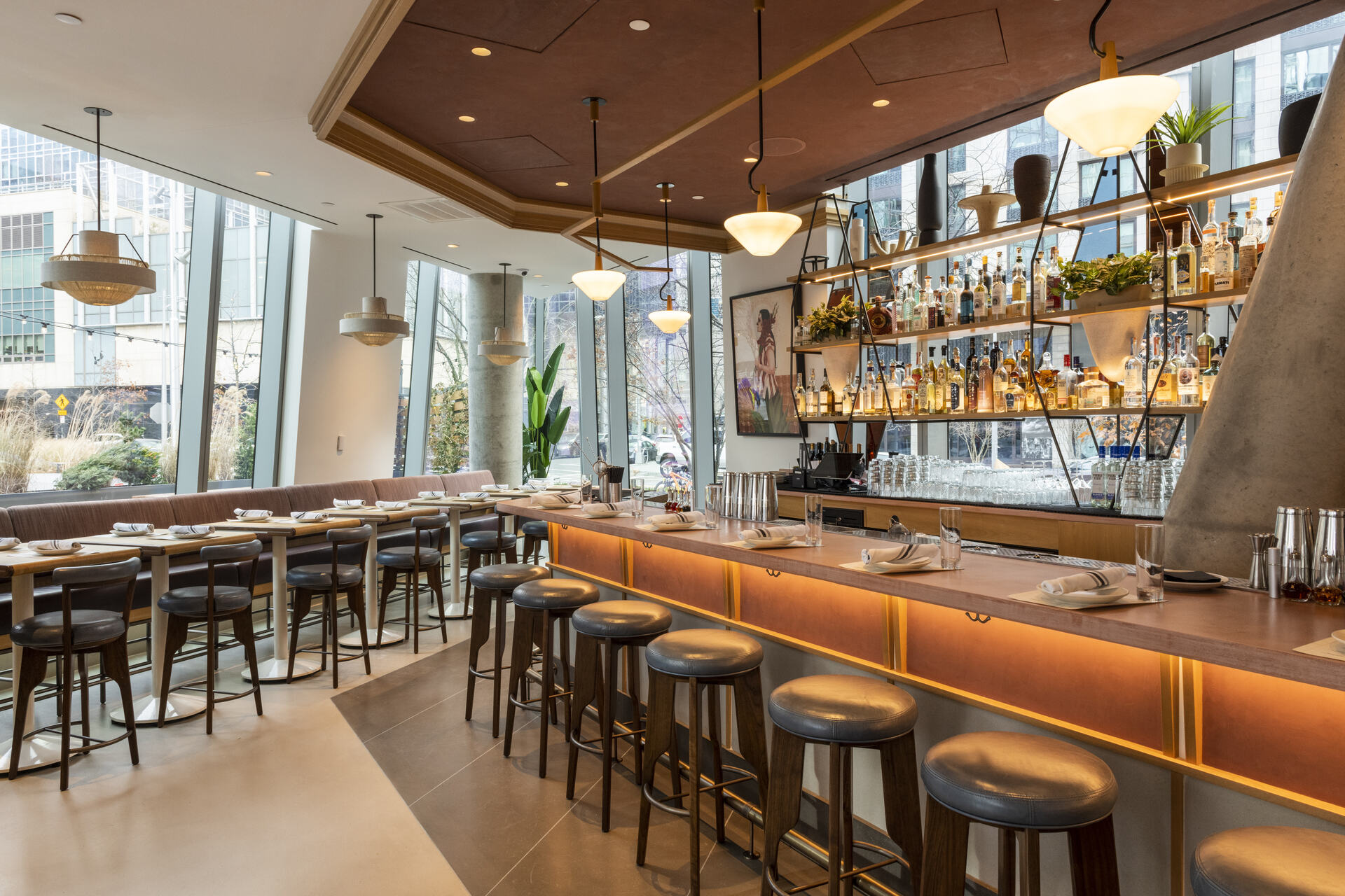 Modern and sophisticated restaurant interior with a stylish bar area, elegant dining tables, and pendant lighting, creating an inviting atmosphere for a fine dining experience.